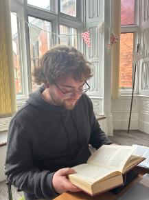 Sam reading a book in front of a window